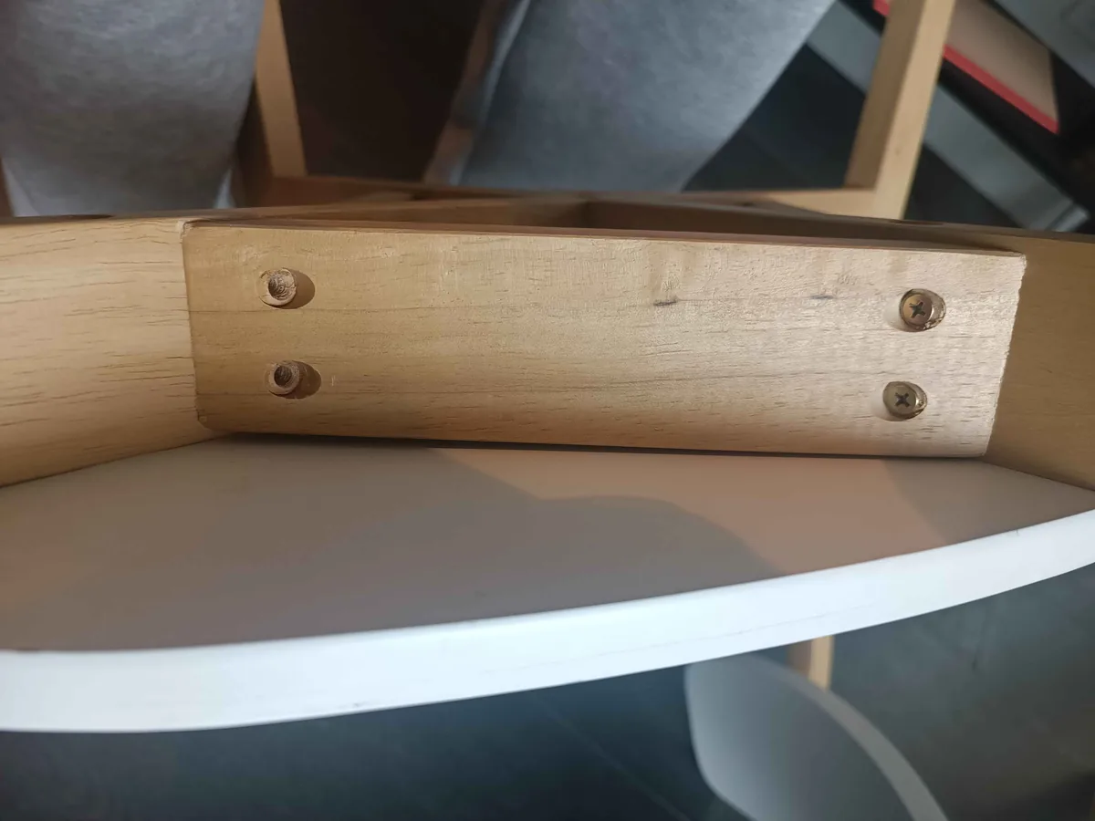 Underside of a curved timber shelf showing a fitted support block and screw fixing points