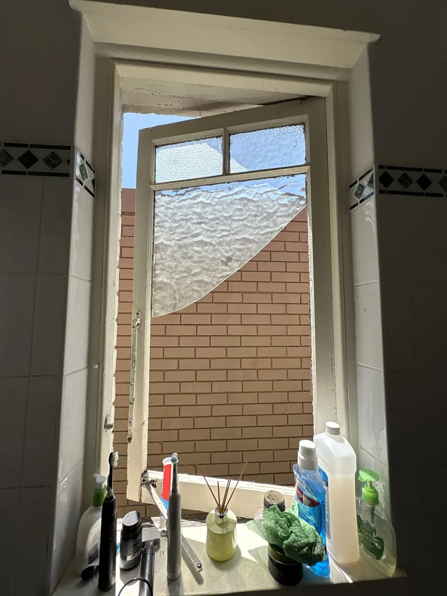 Open timber awning bathroom window with a visibly damaged patterned glass pane