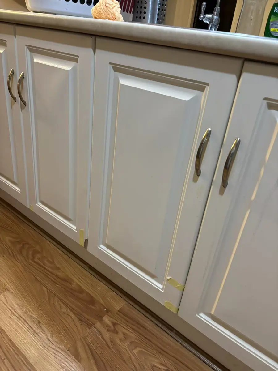 Refitted white base cabinet doors beneath a kitchen benchtop during final alignment