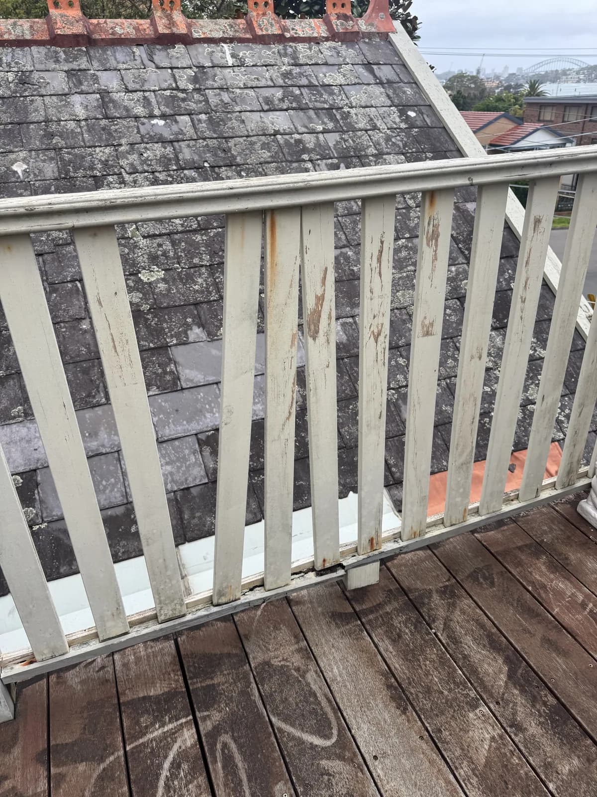Weathered painted timber balustrade with worn coating and staining near the lower rail
