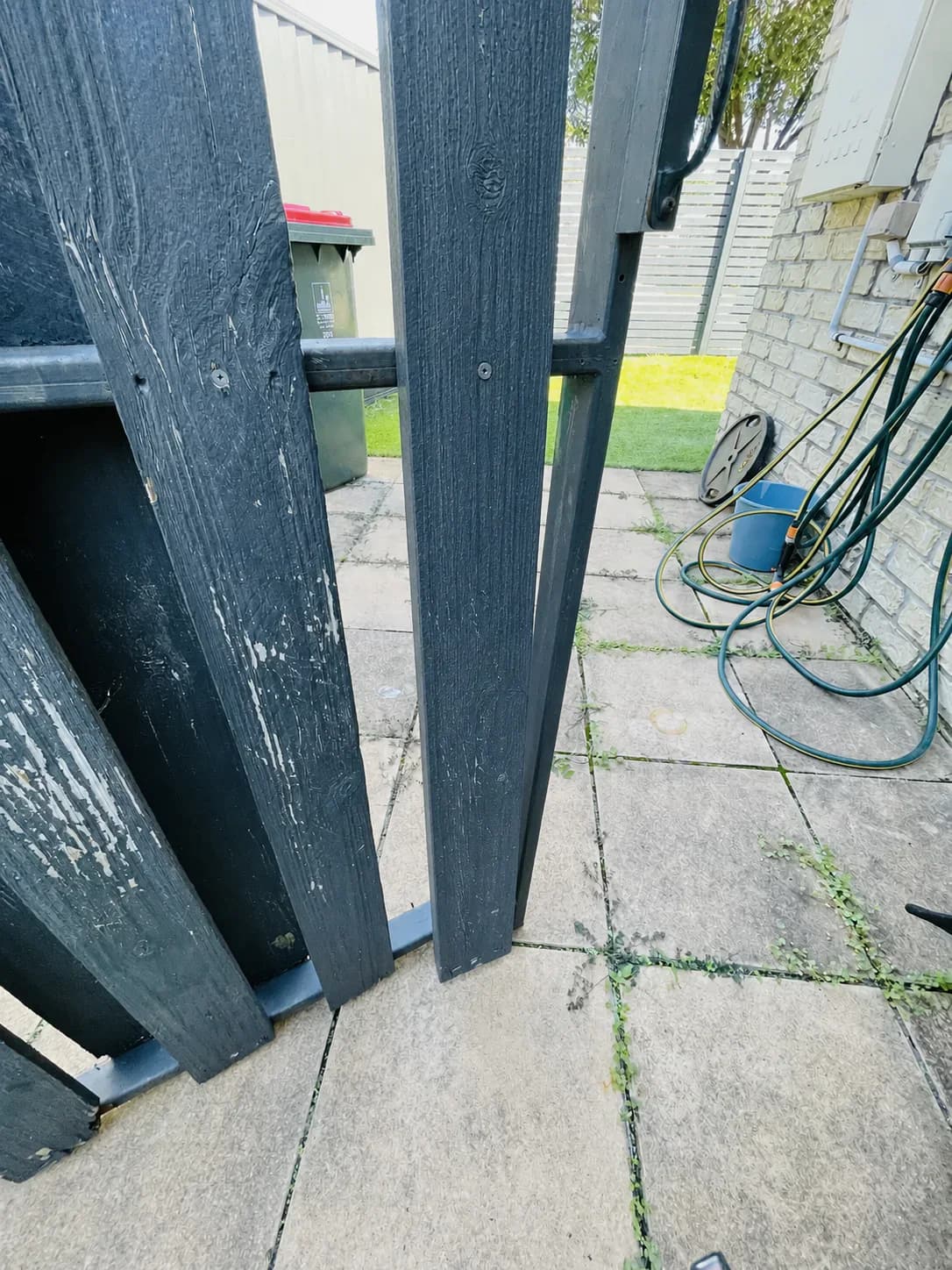 Repaired dark painted gate with the broken central timber paling replaced