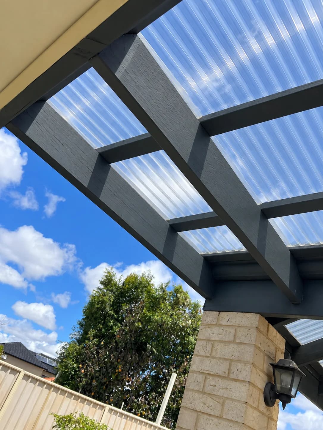 Repaired charcoal pergola beams with translucent roof sheeting fitted