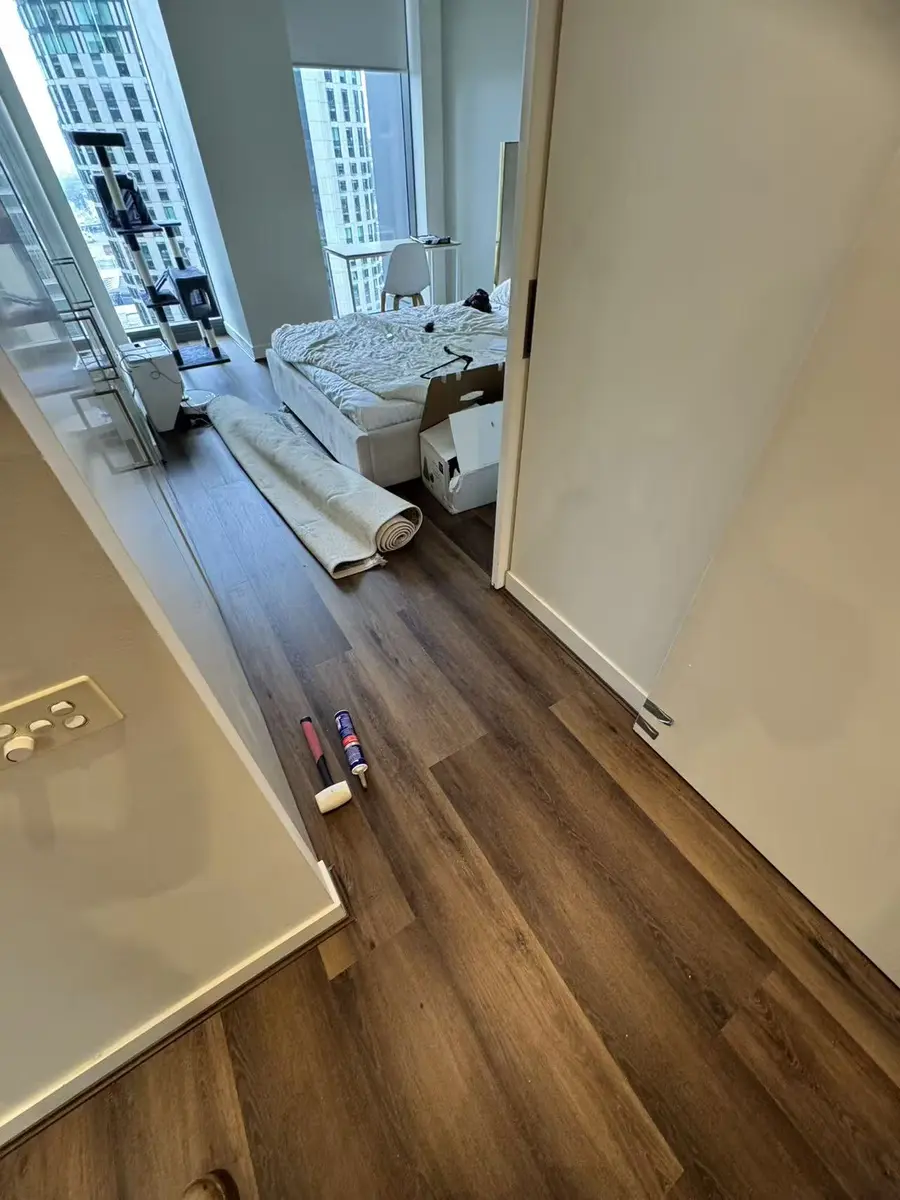 Dark plank flooring in a high-rise bedroom with tools and a rolled rug